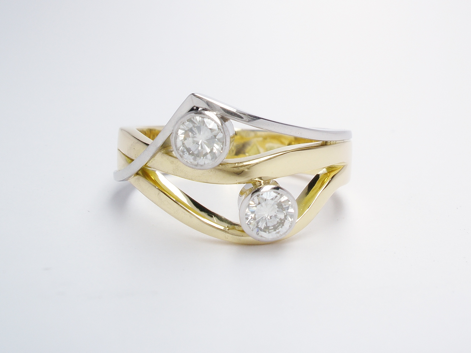 A 2 stone rub-over set round brilliant cut diamond wave & wishbone style ring mounted in 18ct. yellow gold and platinum.