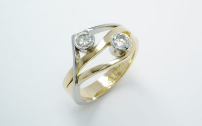 A 2 stone rub-over set round brilliant cut diamond wave & wishbone style ring mounted in 18ct. yellow gold and platinum.