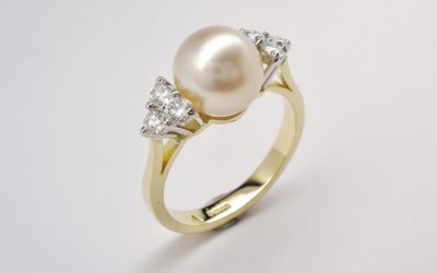 A 9mm South Sea pearl and round brilliant cut diamond 7 stone ring mounted in 18ct. yellow gold and platinum.