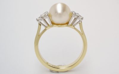 A 9mm South Sea pearl and round brilliant cut diamond 7 stone ring mounted in 18ct. yellow gold and platinum.