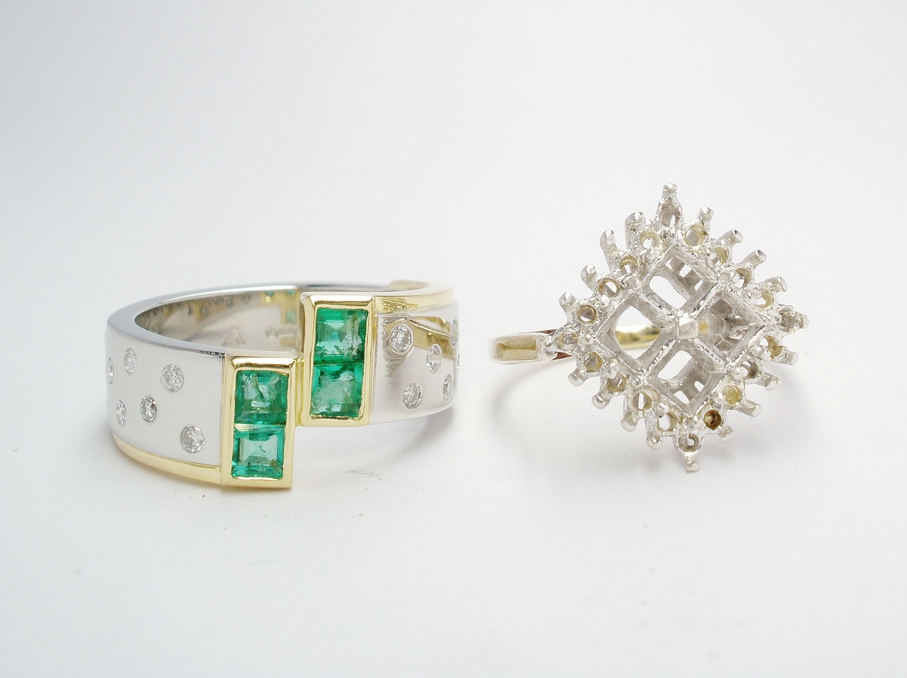 The 4 square cut emeralds rub-over set in 2 pairs creating a cross-over style and the diamonds flush set into the broad platinum shank. Finished
