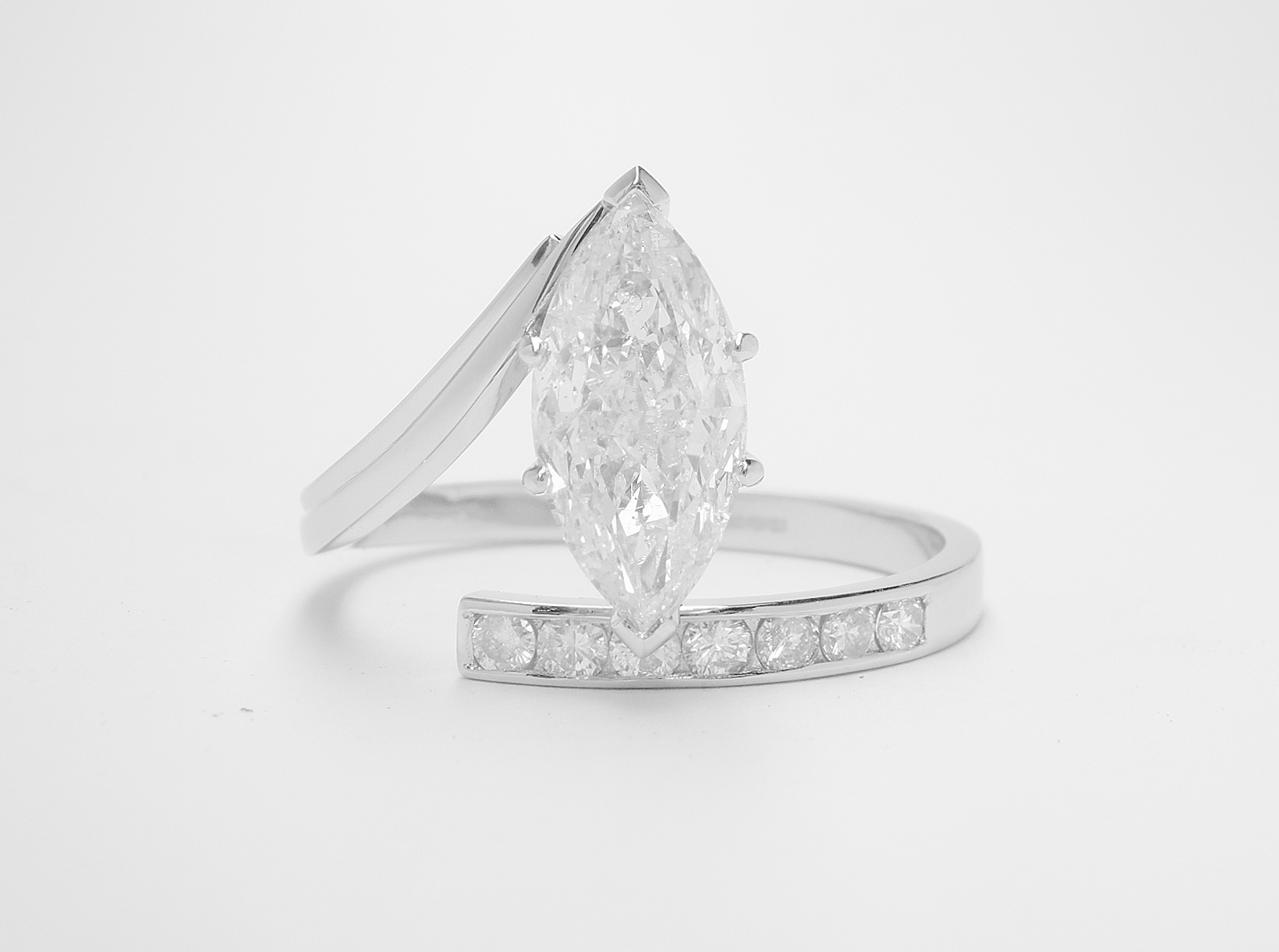 A 1.71ct. 'F' colour, SI clarity, marquise straight wishbone cross-over style ring mounted in platinum with 7 round brilliant cut diamonds channel set in the straight shoulder.