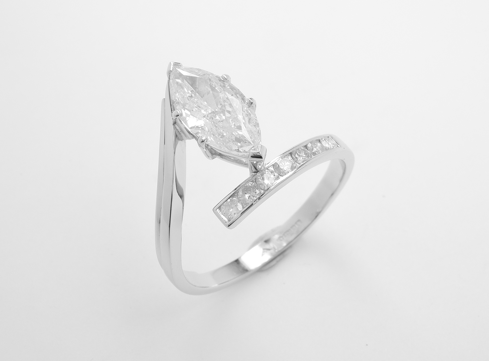 A 1.71ct. 'F' colour, SI clarity, marquise straight wishbone cross-over style ring mounted in platinum with 7 round brilliant cut diamonds channel set in the straight shoulder.