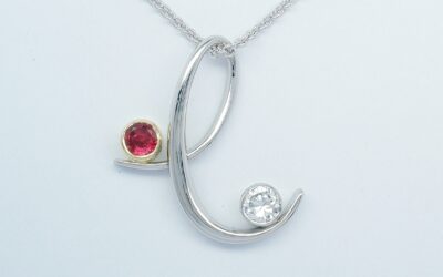 A ruby and diamond stylised 'e' platinum pendant.