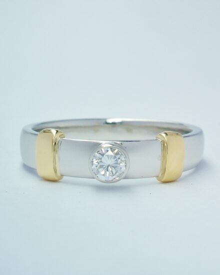 A platinum and 18ct yellow gold rub-over set single stone diamond dress ring.