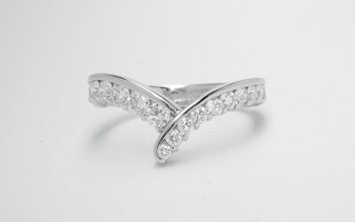 A 19 stone part channel set wishbone cross-over styled ring mounted in platinum. There are 12 tapering diamonds on the right side and 7 of the same size on the left side.