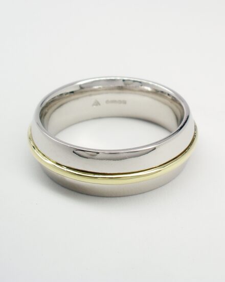 A platinum court sectioned wedding ring with an 18ct. Green gold wire inlayed in the centre.