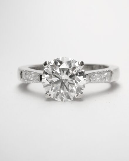 Before A single stone 1.50cts. round brilliant cut diamond ring with tapered baguette shoulders set in 18ct. white gold.