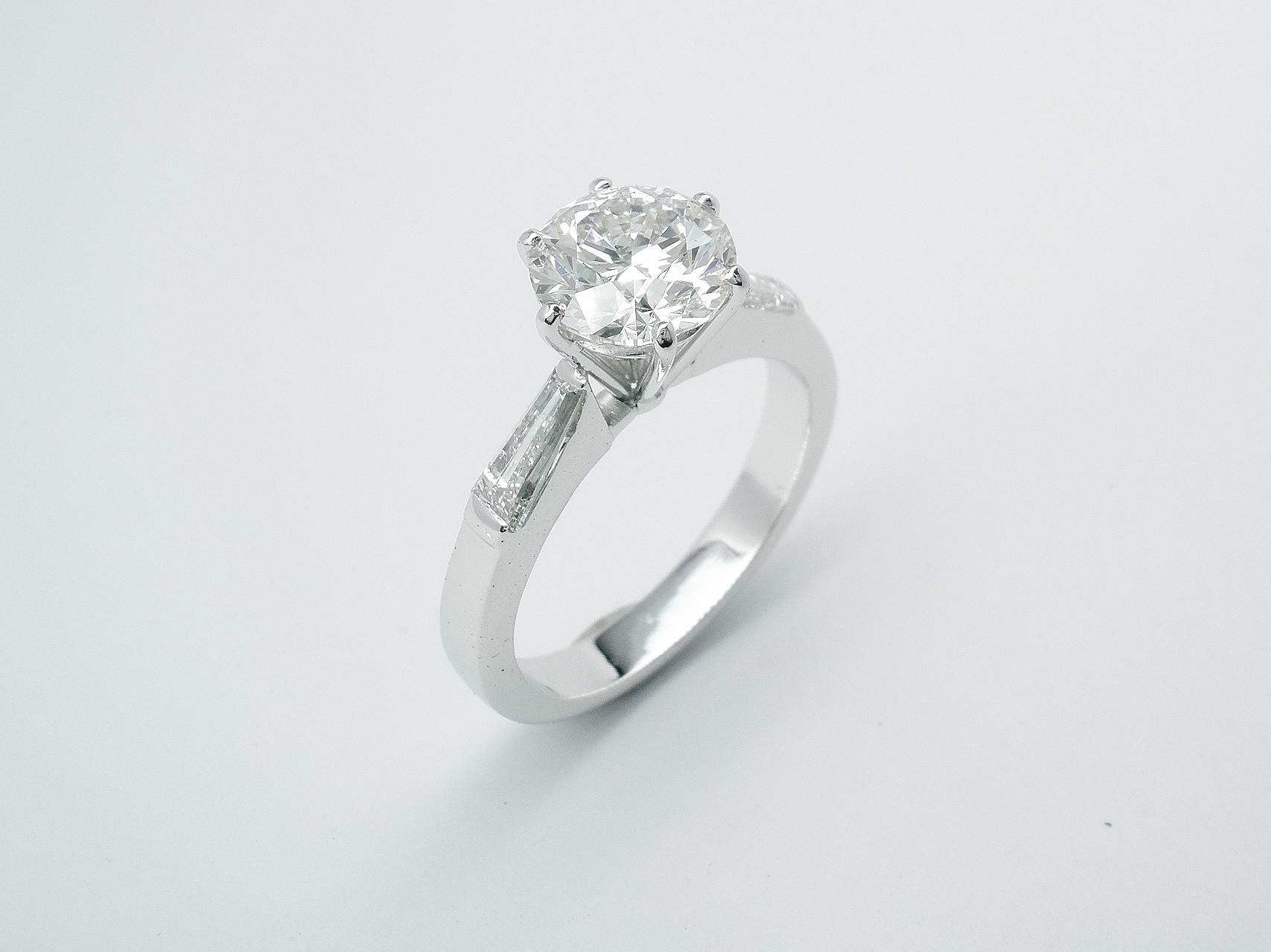 After The 1.50cts. round brilliant cut diamond set in a handmade higher platinum setting inserted successfully between the original tapered baguette shouldered 18ct white gold mount.
