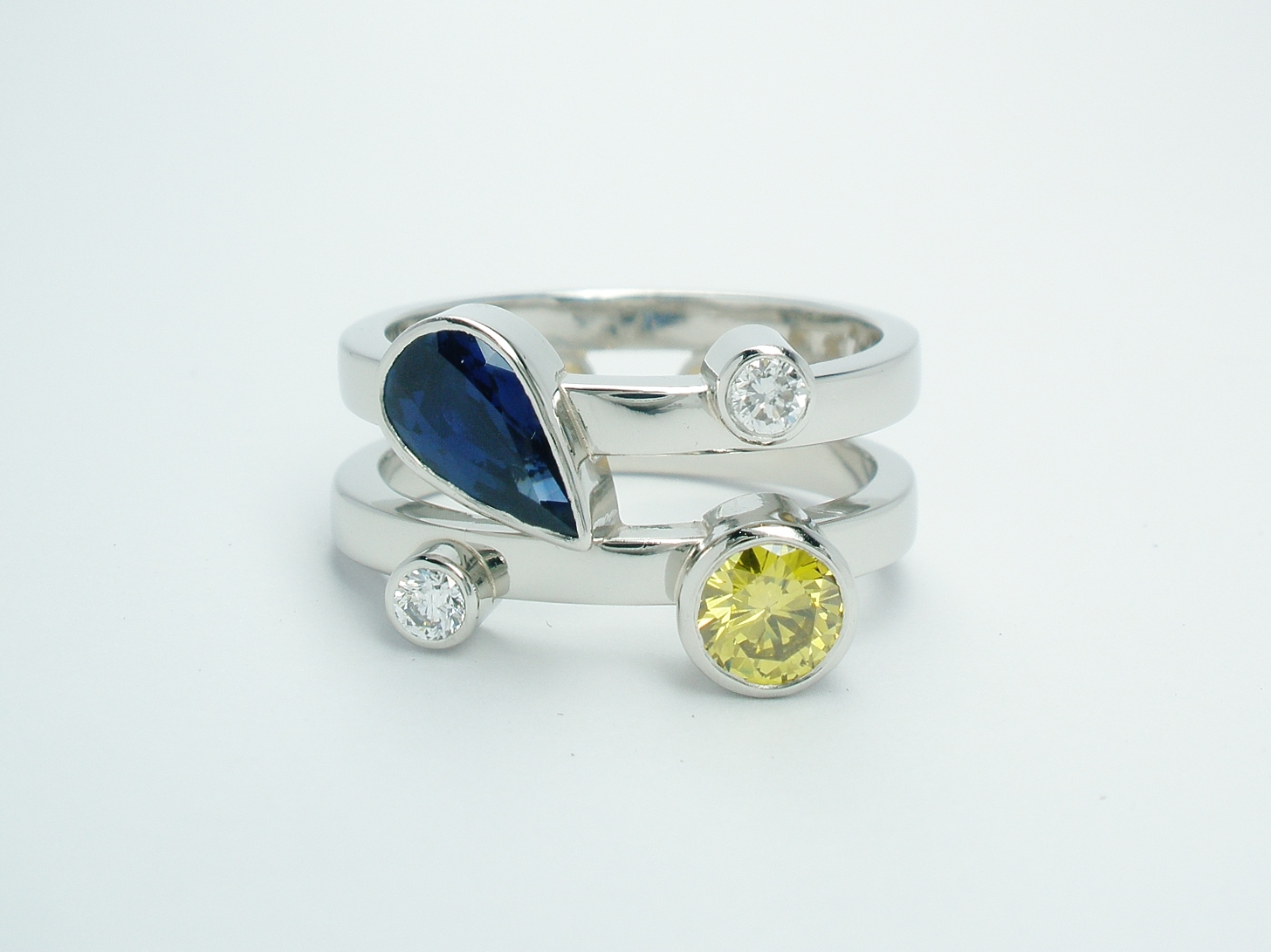 A platinum 4 stone pear sapphire, canary yellow & white round brilliant cut diamond twin parallel banded ring.