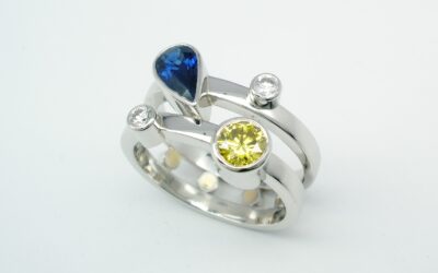 A platinum 4 stone pear sapphire, canary yellow & white round brilliant cut diamond twin parallel banded ring.