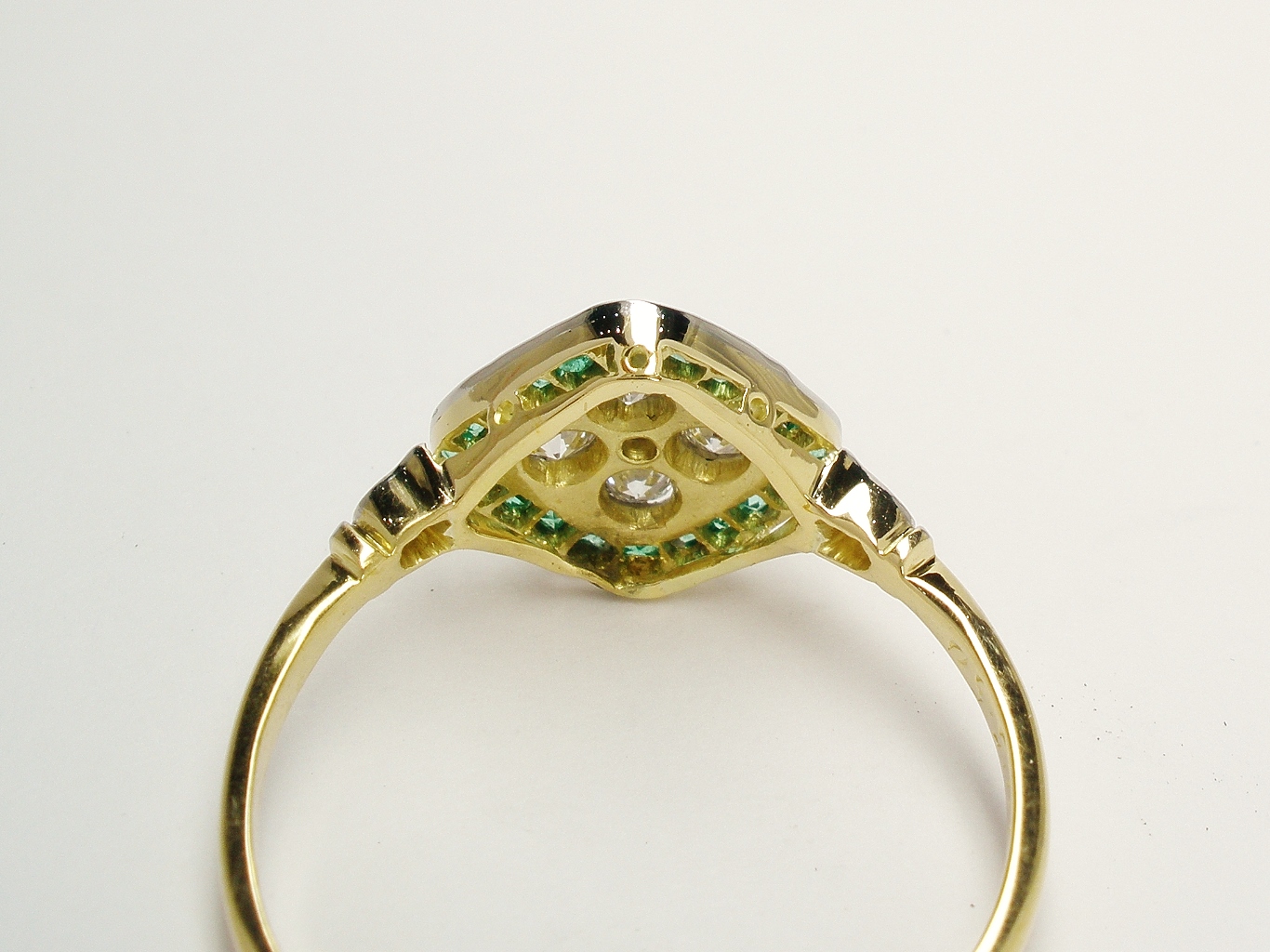 The 18ct. yellow gold back rail repaired and built up and the very fine platinum setting replaced & the emeralds reset.