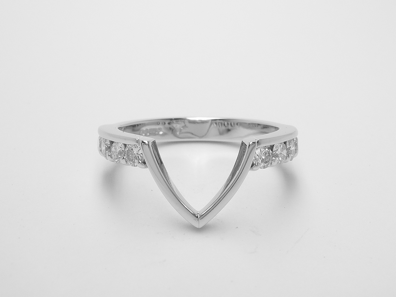 A 10 stone round brilliant cut part channel set platinum wedding ring with central 'V' wire to fit around a marquise cluster engagement ring.