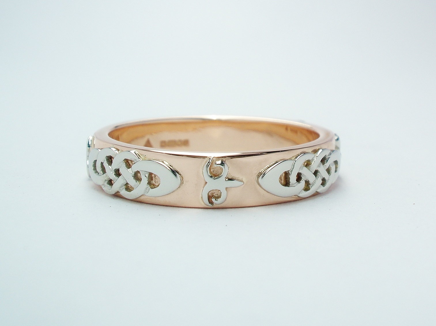 A red gold gent's wedding ring with platinum Celtic and Kazakh style motif overlays.