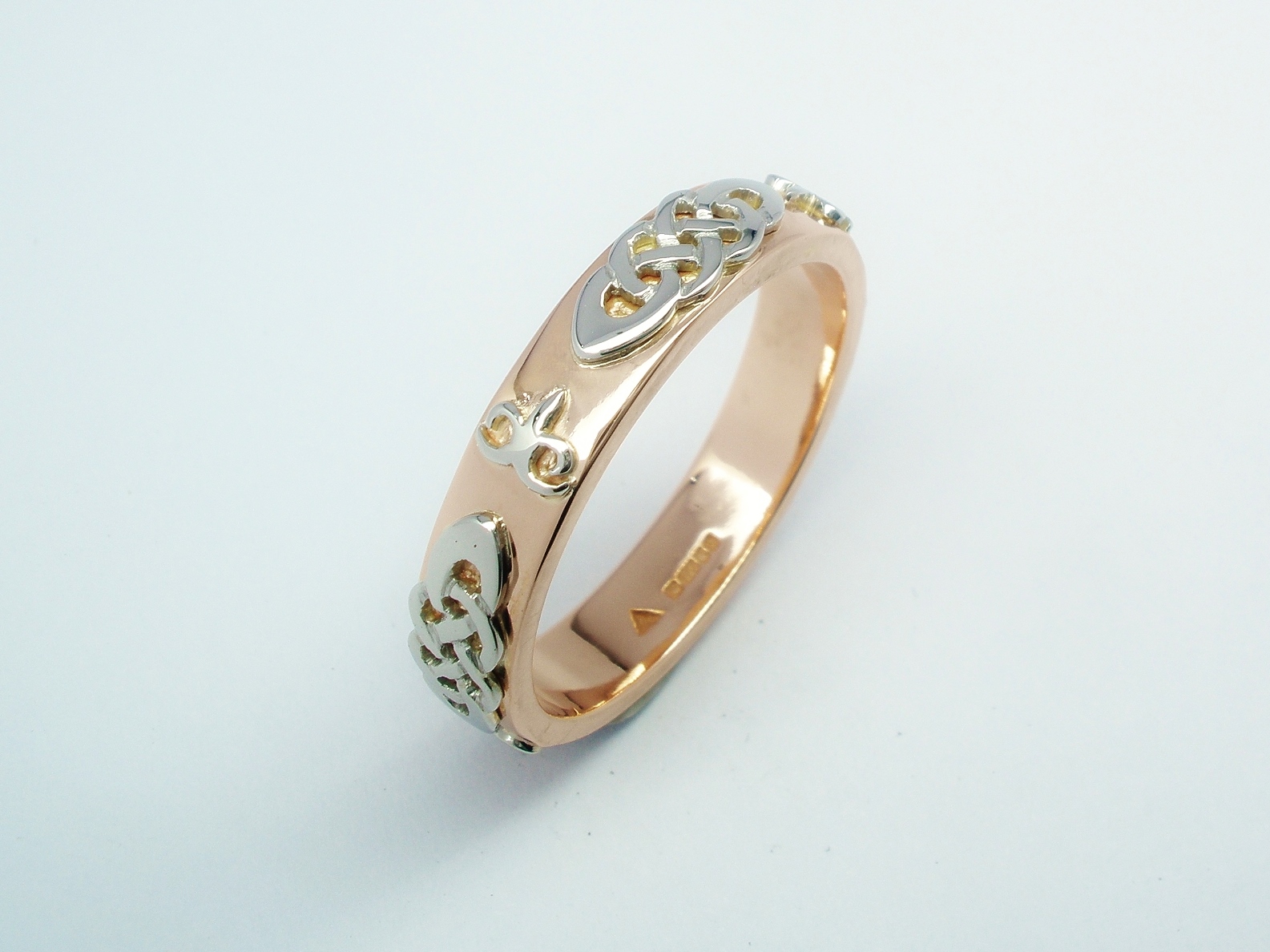 A red gold gent's wedding ring with platinum Celtic and Kazakh style motif overlays.