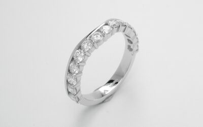 A 14 stone round brilliant cut part channel set eternity ring mounted in platinum and shaped to fit around a 3 stone diamond ring.