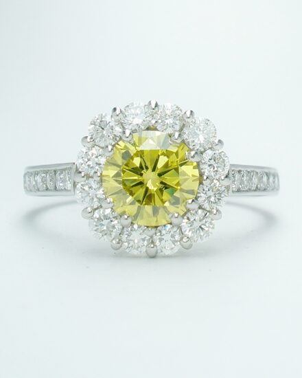 A 13 stone round brilliant cut 'HPHT' canary yellow diamond and white diamond round cluster with 7 round diamonds channel set down each shoulder.