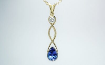 An 18ct. yellow gold hand carved Celtic style drop pendant mounted with a pear shaped tanzanite round brilliant cut diamond rub-over set in platinum.