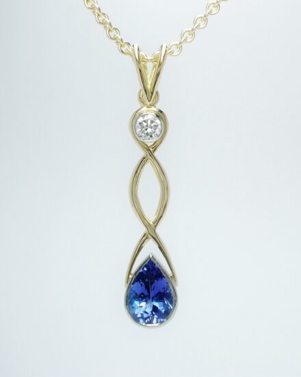 An 18ct. yellow gold hand carved Celtic style drop pendant mounted with a pear shaped tanzanite round brilliant cut diamond rub-over set in platinum.