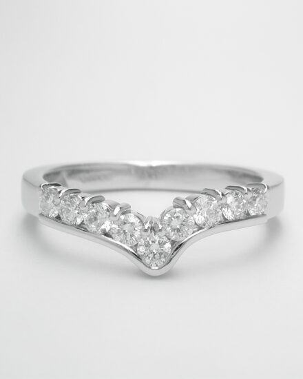 A 9 stone round brilliant cut diamond part channel set shaped eternity ring mounted in platinum.