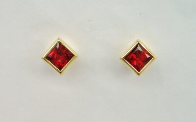 A pair of 3.5mm square princess cut super fine colour ruby earrings rub-over set in 18ct. yellow gold.