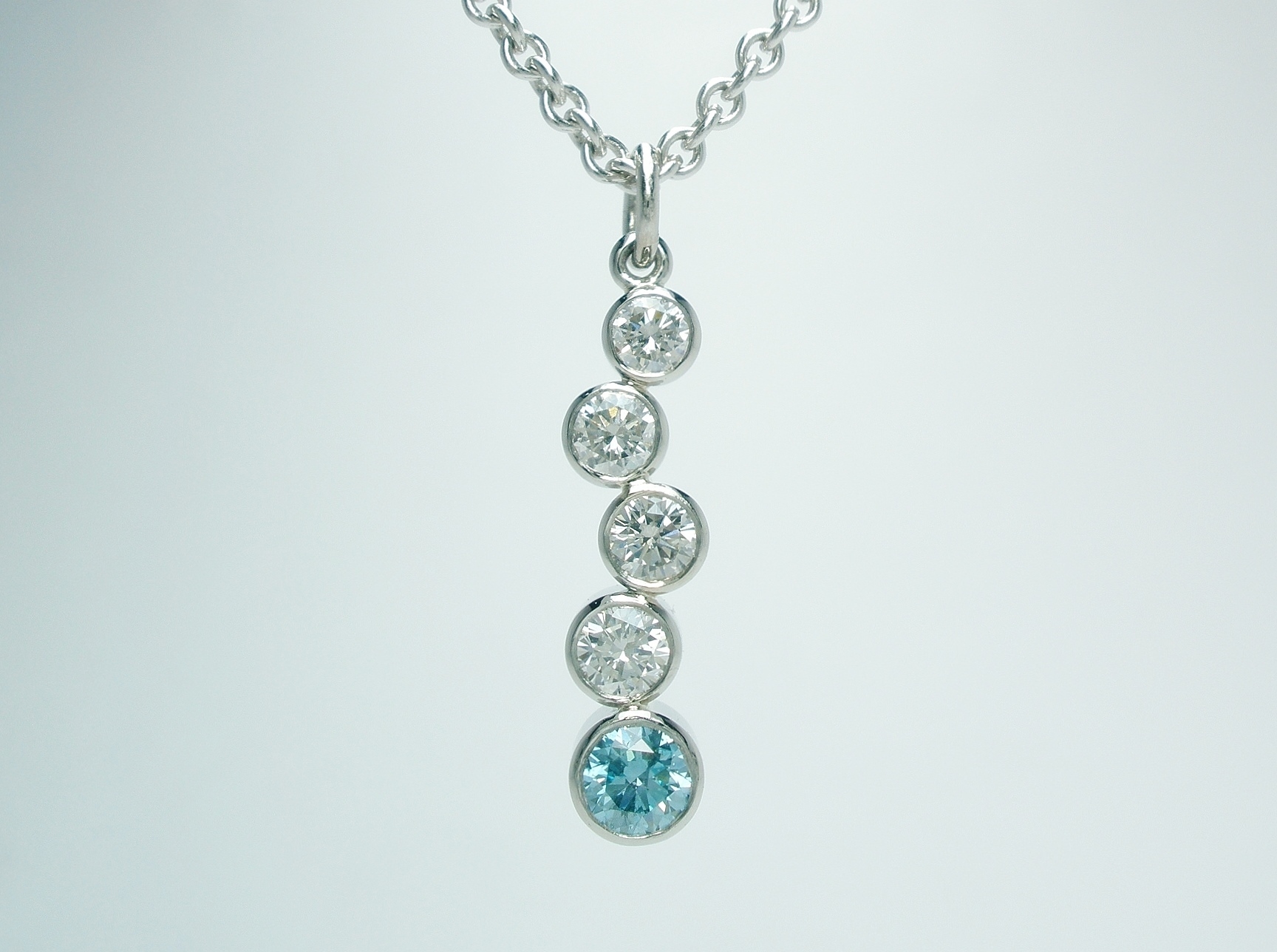5 stone sky blue and white round brilliant cut diamond tumble pendant rub-over set in platinum