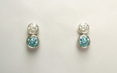A pair of 2 stone sky blue and white diamond ear studs rub-over set in platinum to compliment the 5 stone pendant.