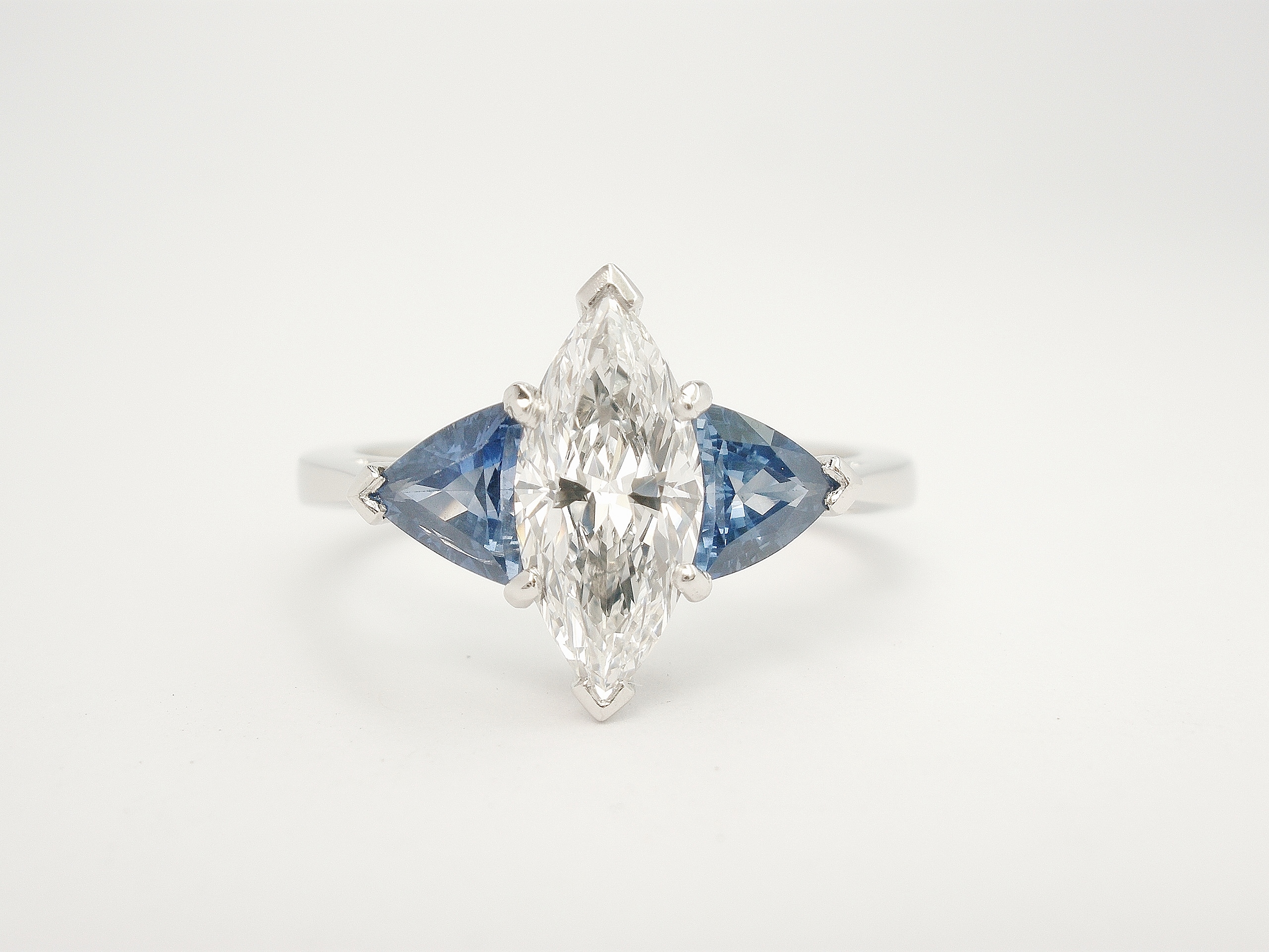 The 3 stone Marquise diamond and trilliant shaped sapphire ring mounted in platinum that has the 14 stone sapphire and diamond part channel set platinum ring shaped to fit.