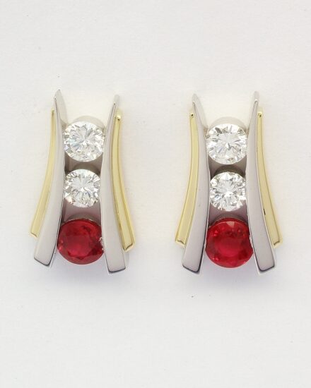 A pair of 3 stone round ruby and round brilliant cut diamond ear studs channel set in platinum, trimmed with 18ct. yellow gold and with 18ct. yellow gold 'guardian' safety fittings.