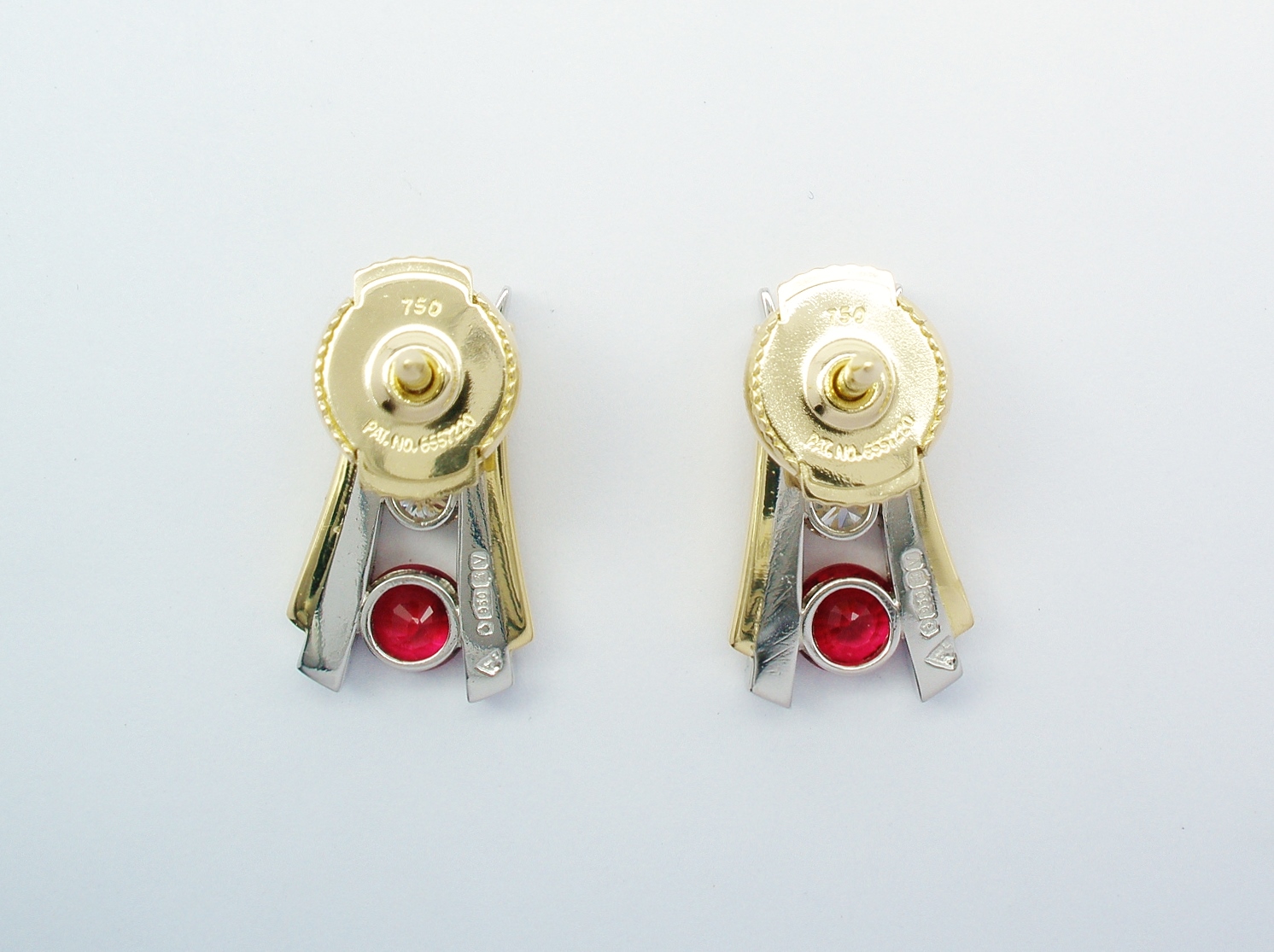 A pair of 3 stone round ruby and round brilliant cut diamond ear studs channel set in platinum, trimmed with 18ct. yellow gold and with 18ct. yellow gold 'guardian' safety fittings.
