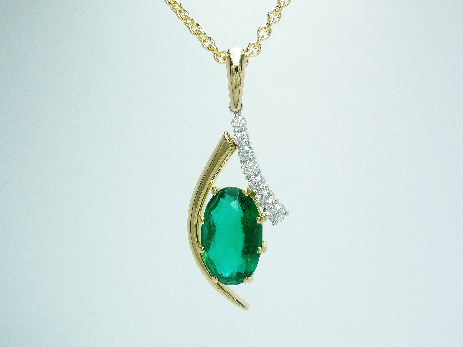 An 8 stone synthetic emerald and round brilliant cut diamond pendant mounted in 18ct yellow gold and platinum. The emerald was supplied by the client & sentimental to them.