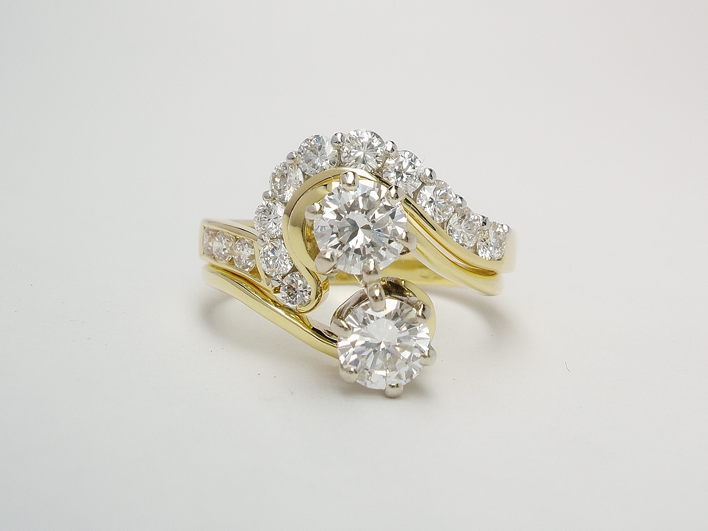 A 13 stone round brilliant cut diamond channel and part channel set ring mounted in 18ct. yellow gold and platinum and shaped to fit around a 2 stone cross-over engagement ring.