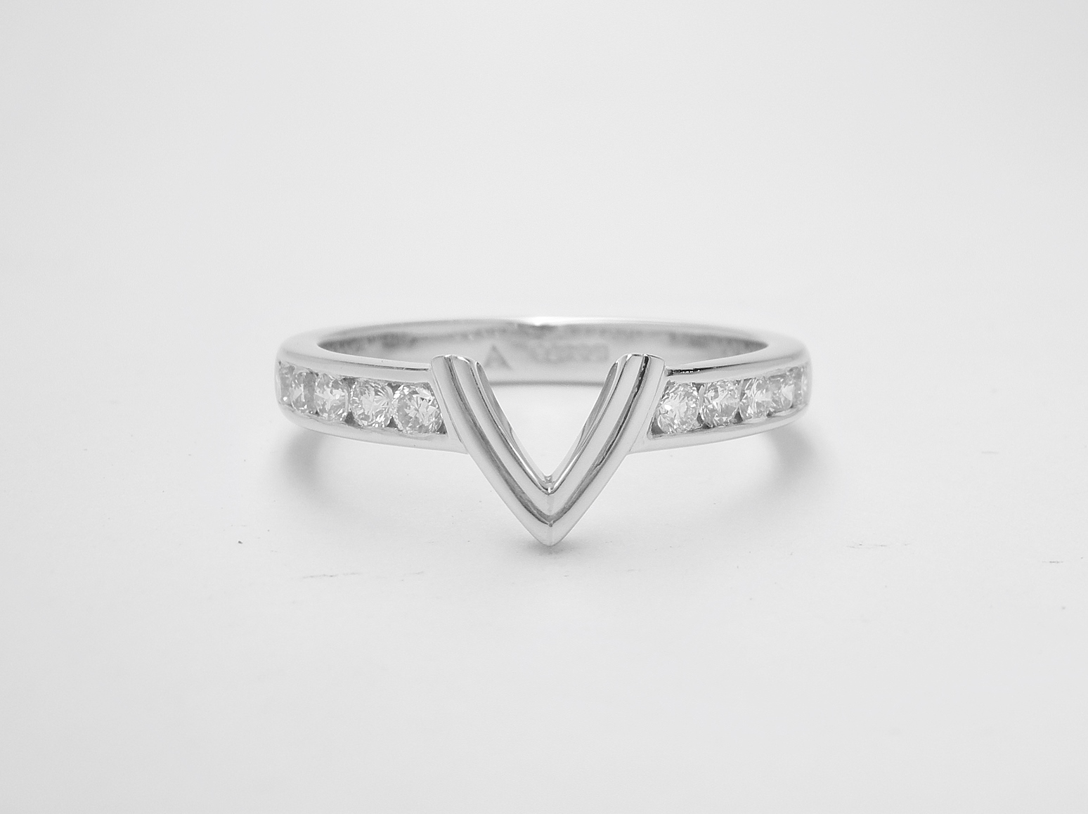 A 10 stone channel set round brilliant cut diamond ring shaped with a central double 'V' wire to fit with a marquise diamond engagement ring.