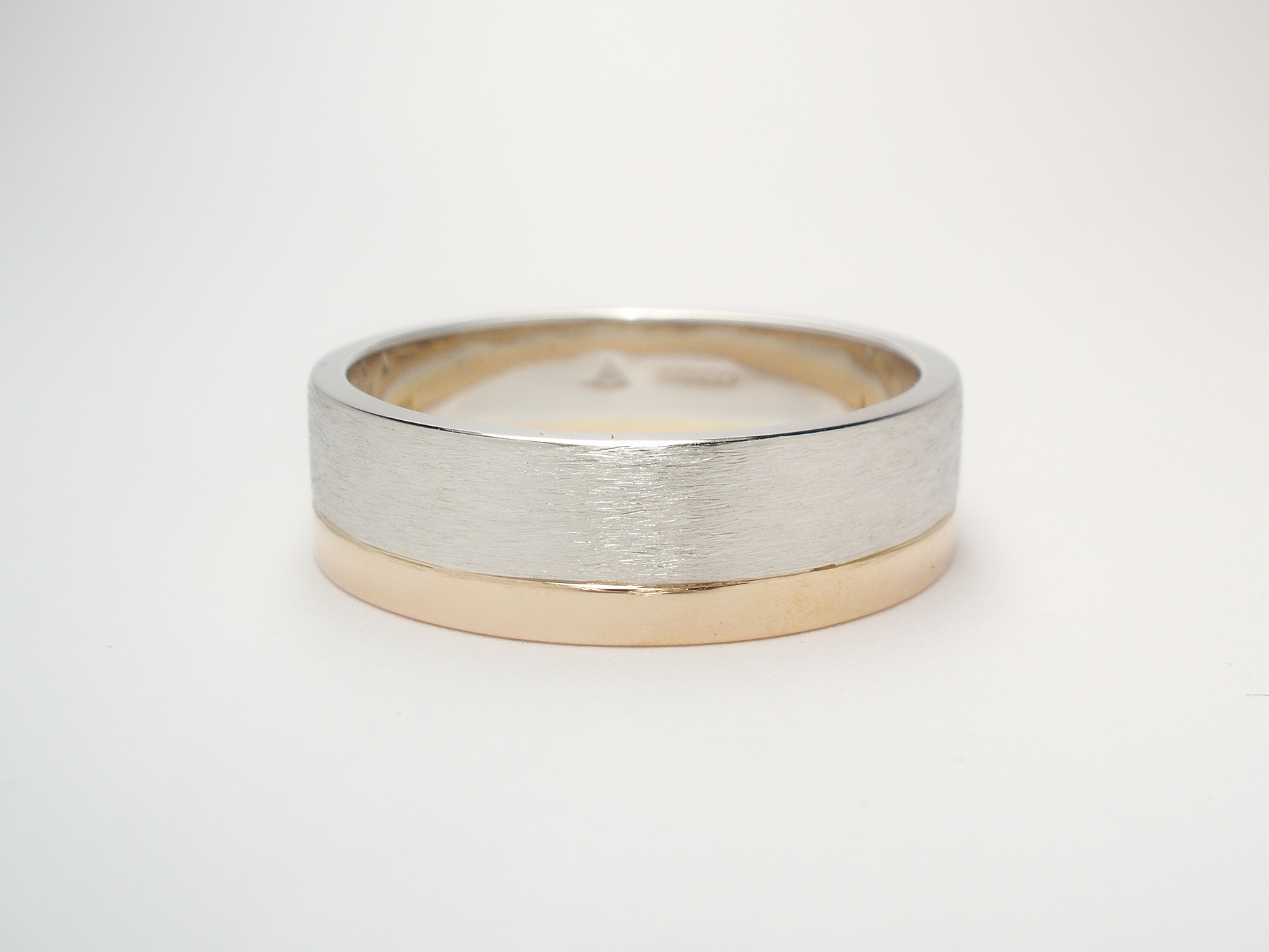 A 4.5mm broad platinum ring brushed finish with a 2mm broad red gold ring applied to one edge.