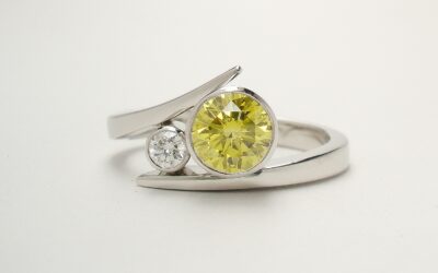 A 2 stone HPHT treated canary yellow and white round brilliant cut straight wishbone cross-over diamond ring. Mounted in platinum.