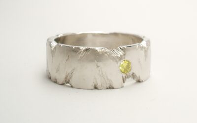 An 8mm broad platinum ring with fractured rock effect and flush set with a 2.8mm HTHP treated canary yellow diamond.