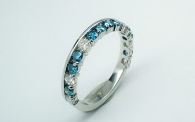A 16 stone Sky Blue and white round brilliant cut diamond part channel set wedding ring. The pattern of Blue to white is 4 blue, 1 white, 2 blue, 1 white, 1 blue, 1 white.
