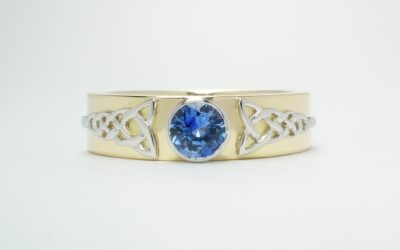 An 18ct. yellow gold single stone round Ceylon sapphire rub-over set in platinum with a fine platinum Celtic motif overlaid on both sides.