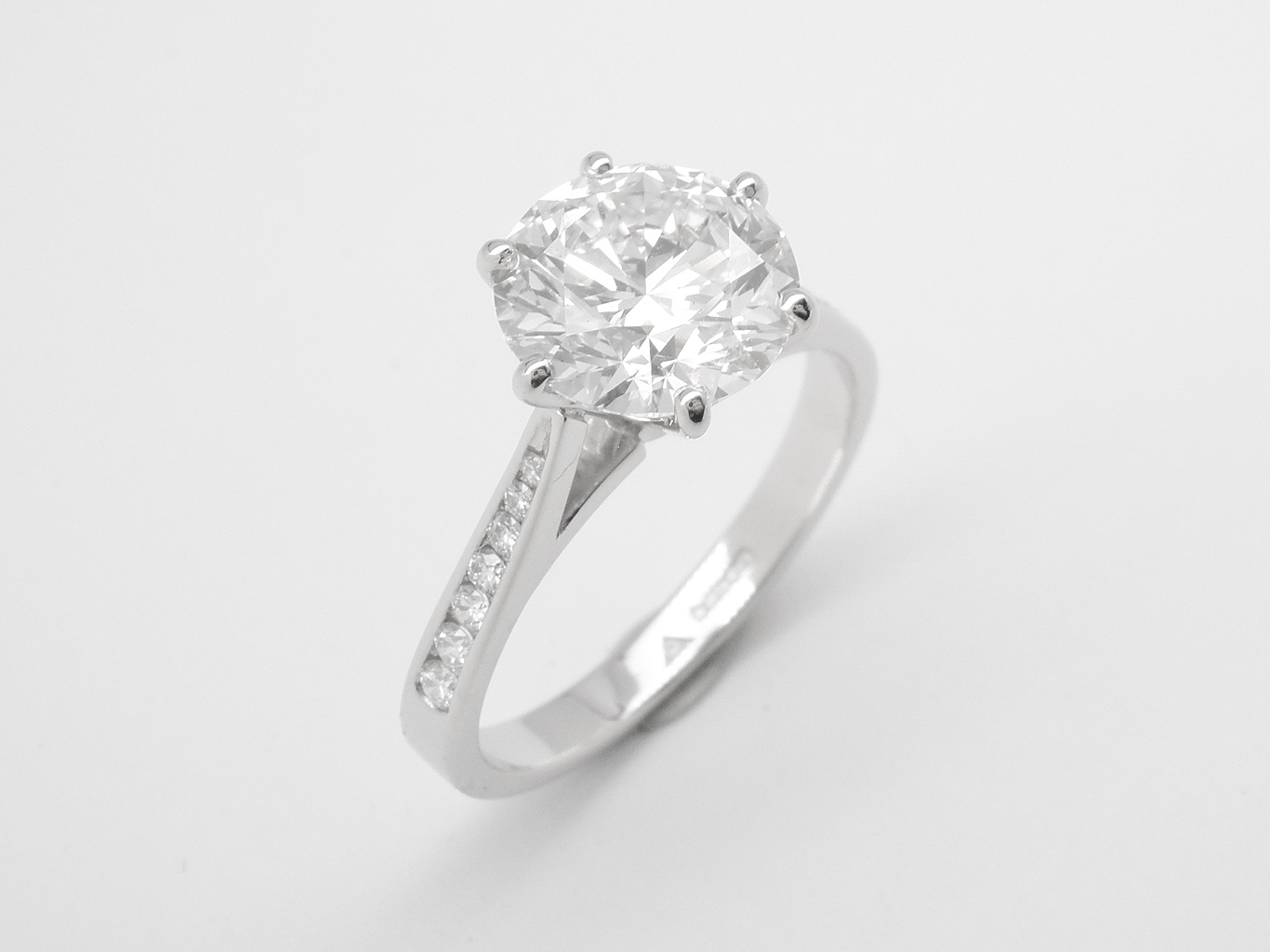 A 2.26cts round brilliant cut diamond ring mounted in platinum with 7 round brilliant cut diamonds that taper in size channel set in each shoulder.