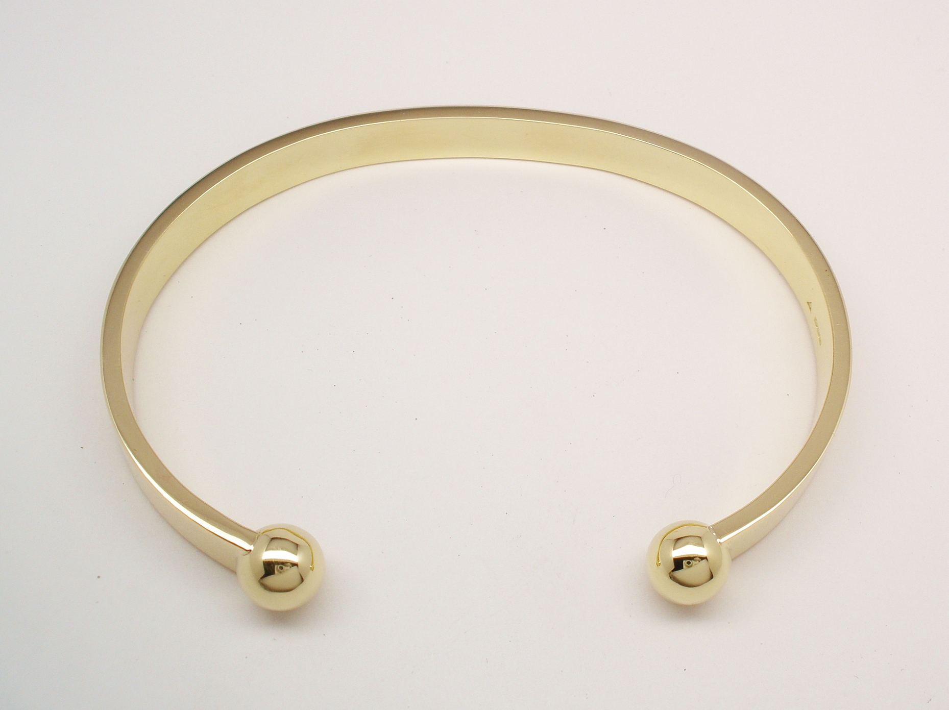 A gents 9ct yellow gold torque bangle with solid ball ends.