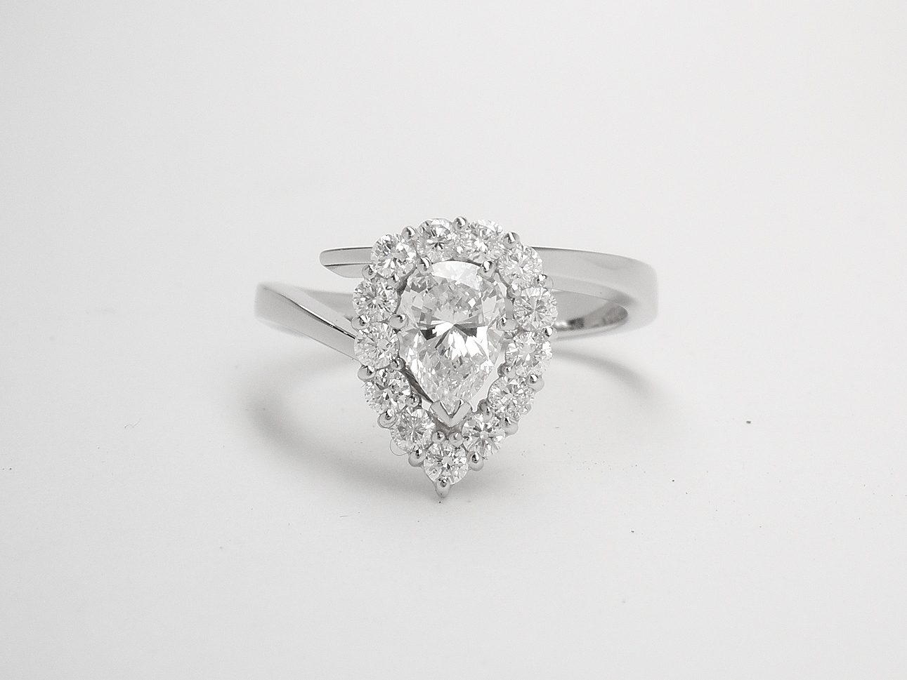A 14 stone pear shaped 'Halo' cluster straight wishbone cross-over styled ring mounted in platinum.