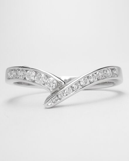 A 15 stone channel set round brilliant cut wedding ring mounted in platinum and shaped to fit with a single stone diamond wishbone style ring.