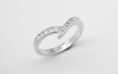 A 15 stone channel set round brilliant cut wedding ring mounted in platinum and shaped to fit with a single stone diamond wishbone style ring.