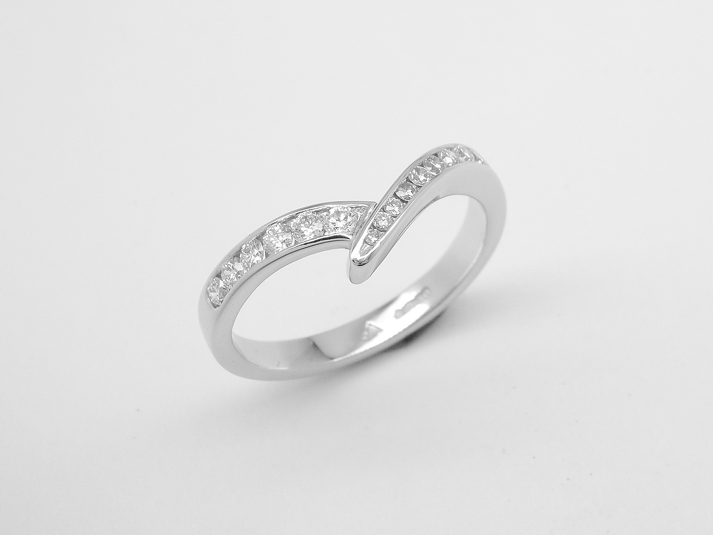 A 15 stone channel set round brilliant cut wedding ring mounted in platinum and shaped to fit with a single stone diamond wishbone style ring.