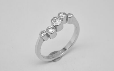 A rub-over set 5 stone round brilliant cut diamond 'zig-zag' style ring mounted in platinum.