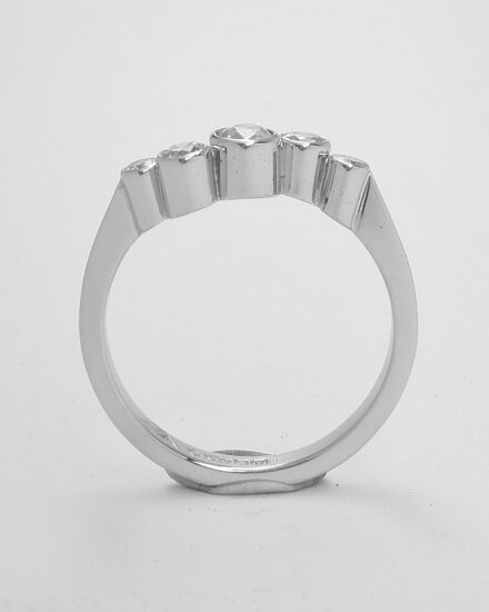 A rub-over set 5 stone round brilliant cut diamond 'zig-zag' style ring mounted in platinum.