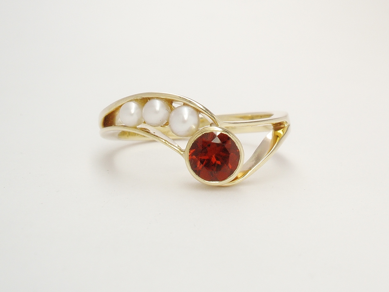 A 4 stone round garnet and pearl 'wishbone' style ring mounted in 9ct. yellow gold.