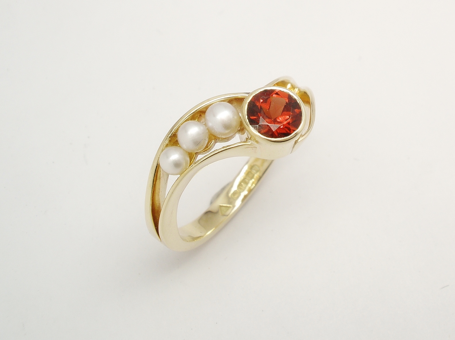 A 4 stone round garnet and pearl 'wishbone' style ring mounted in 9ct. yellow gold.