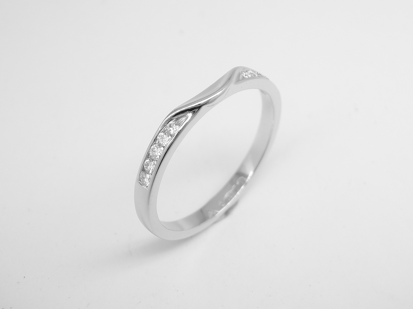 10 stone channel set round brilliant cut platinum wedding ring shaped to fit with single stone round brilliant cut