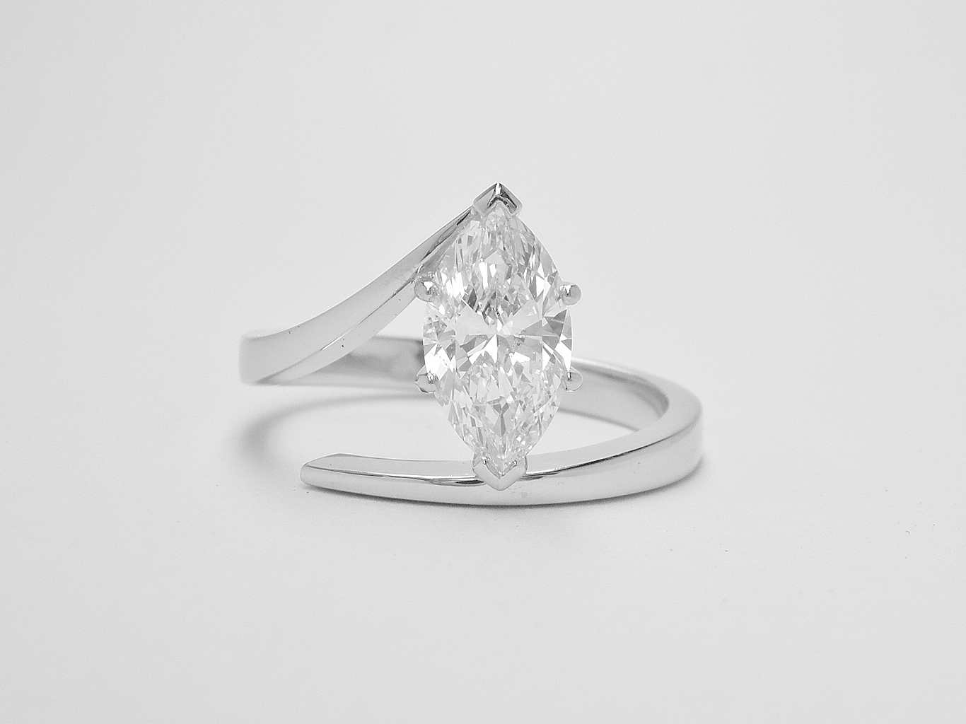 A single stone marquise diamond straight wishbone cross-over style ring mounted in platinum.